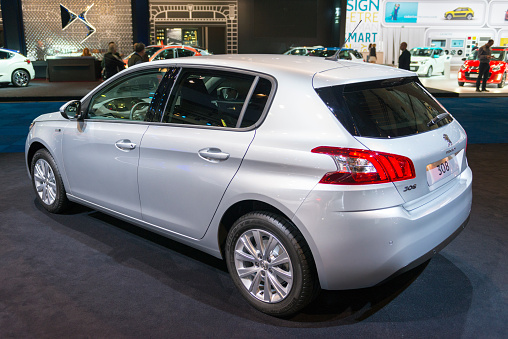 Brussels, Belgium - Januari 12, 2016: Grey Peugeot 308  hatchback car rear view. The car is on display during the 2016 Brussels Motor Show. The car is displayed on a motor show stand, with lights reflecting off of the body. There are people looking around and other cars on display in the background.