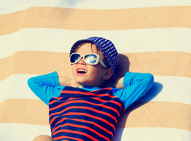 istock cute little boy lying on towel at beach 506557440