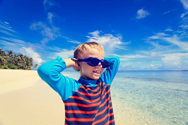 istock happy boy in swimming goggles on beach 506557740