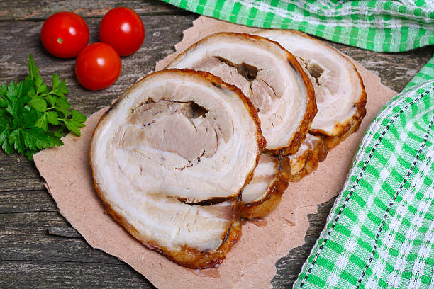 istock Sliced roasted roll pork loin with spices and fresh vegetables 506558072
