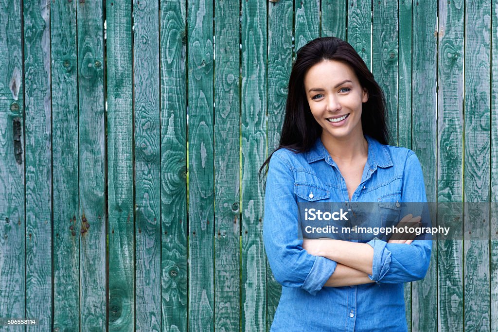 Confident woman smiling with arms crossed Portrait of a confident woman smiling with arms crossed Denim Shirt Stock Photo
