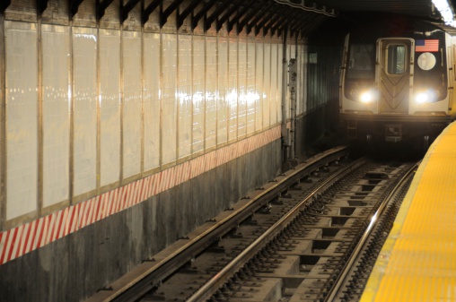 Crowd of people in a NYC subway station waiting for the train at rush hour.