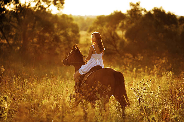 Young woman riding a horse at sunset