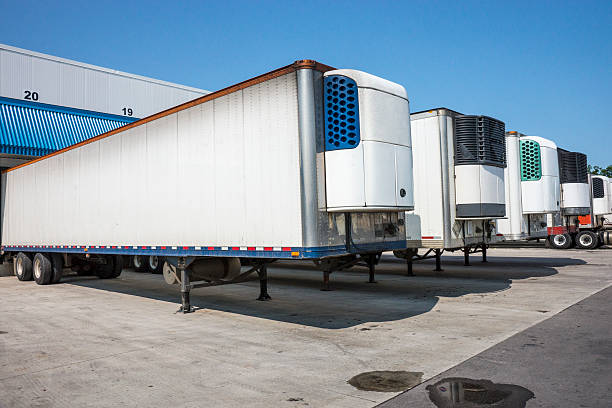 Autocarri, rimorchi refrigerati in un deposito per la distribuzione - foto stock