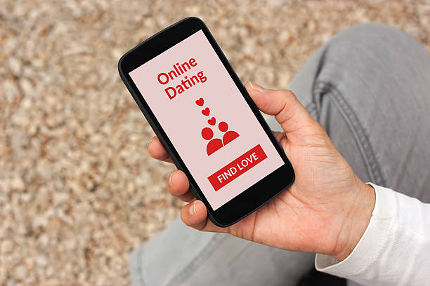 рука держит смартфон с указанием приложения на экране онлайн - internet dating dating togetherness internet стоковые фото и изображения