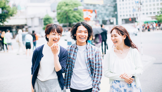 Young asian people  walking  against Tokyo cityscape.  All people in the image are  worn with casual clothes. Background is blurred  buildings around Shibuya crossing in Tokyo. Concept for urban lifestyle and friendship. Image is taken during Tokyo Istockalypse 2015
