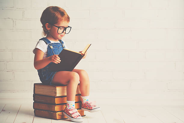 子小さな女の子、眼鏡リーティング、書籍 - child ideas inspiration expertise ストックフォトと画像