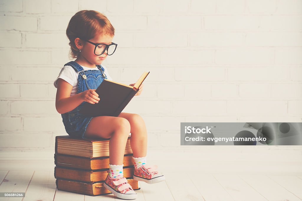 child little girl with glasses reading a books happy child little girl with glasses reading a books Child Stock Photo