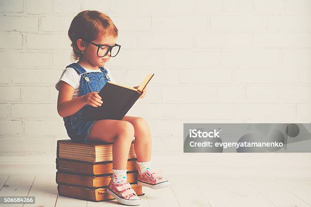 Child Little Girl With Glasses Reading A Books Stock Photo - Download Image Now - Child, Reading, Humor