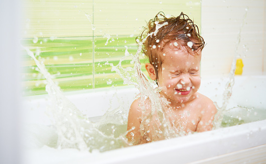 happy baby child bathes in a bath sprinkles and plays with the foam and bubbles