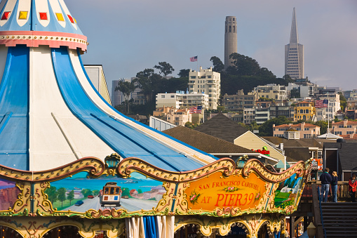 San Francisco, California, USA - May 27, 2005: Carousel at Fisherman's Wharf, Pier 39 with Coit Tower and Transamerica pyramid in the  background. Numerous tourists are visiting this popular area of Fishermans Wharf which offers many attractions, shops and restaurants.