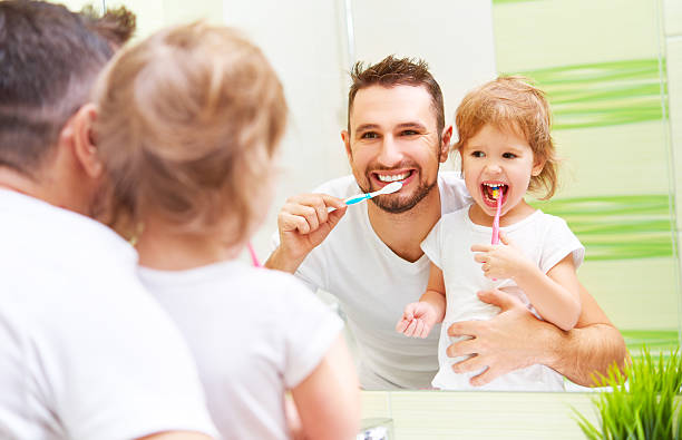 Happy family father and child girl brushing her teeth Happy family father and daughter child girl brushing her teeth in the bathroom toothbrushes brushing teeth stock pictures, royalty-free photos & images