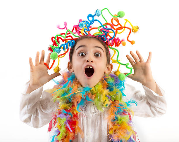 Little party girl having fun laughing and waving her hands excitedly at the camera with colorful streamers in her hair and feathers around her neck