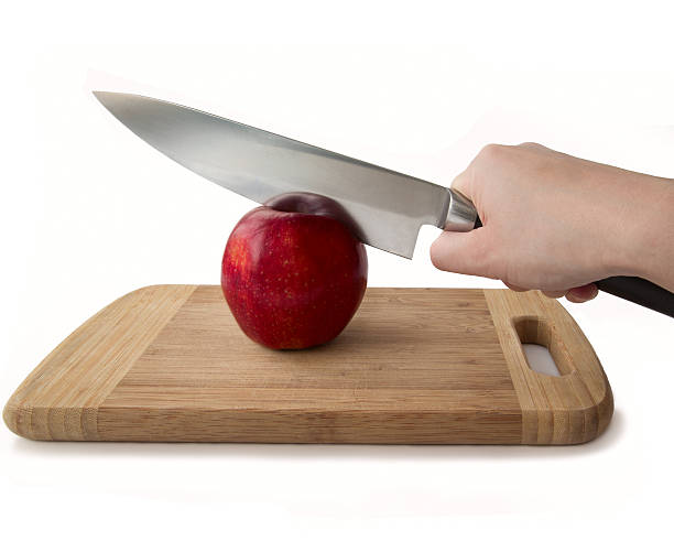 Human hand holding a knife and a red apple stock photo