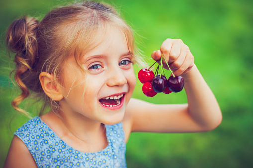 Happy little girl is about to eat a cherry