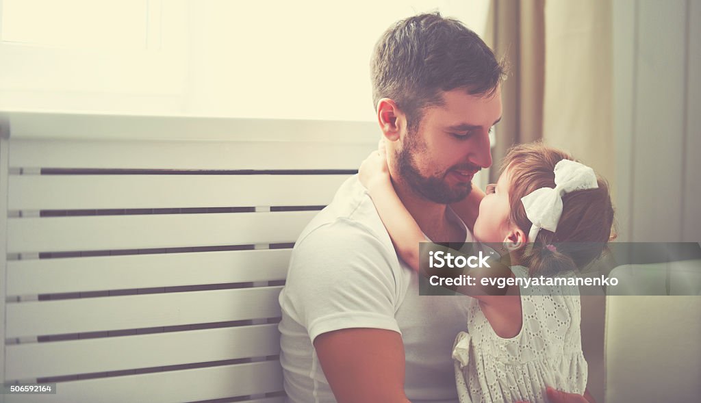 happy family child baby girl in arms of his father happy family child baby girl in the arms of his father at home window Father Stock Photo