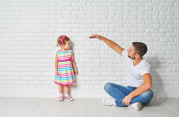 istock concept. Dad measures growth of her child daughter 506592640