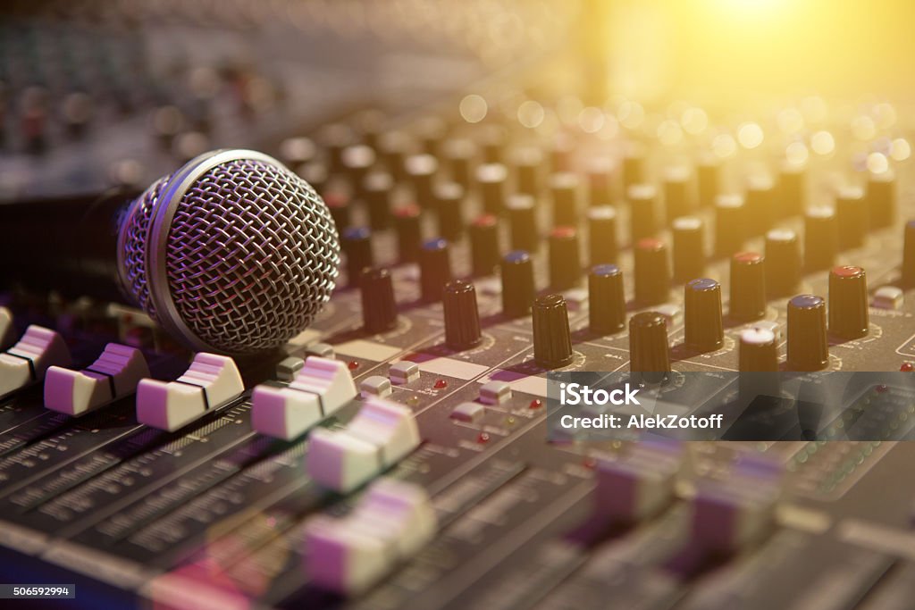 Microphone resting on a sound console Microphone resting on a sound console in a recording studio Sound Mixer Stock Photo