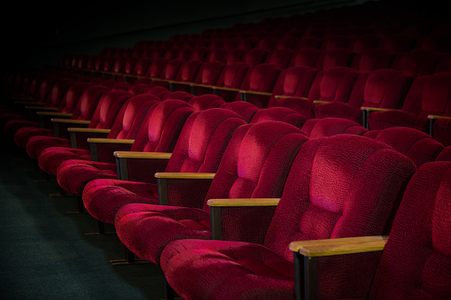 Red velvet armchairs in the empty auditorium. Empty hall