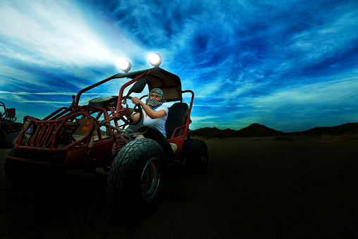 fun time in the desert, young woman enjoying a ride on the atv in the desert.