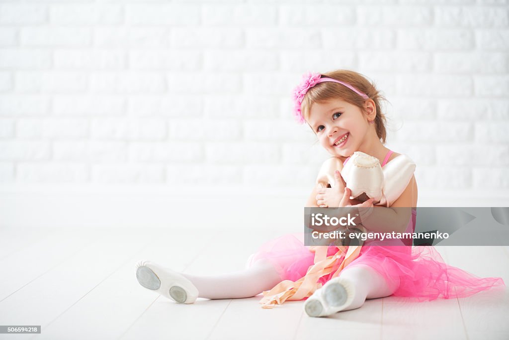 little child girl dreams of becoming  ballerina with ballet shoe little child girl dreams of becoming  ballerina with ballet shoes and pointe shoes in a pink tutu skirt Ballet Stock Photo