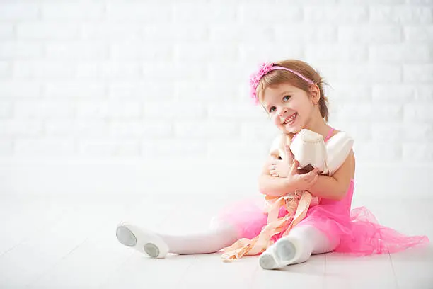 Photo of little child girl dreams of becoming  ballerina with ballet shoe