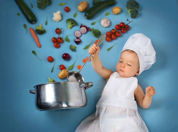 istock Baby boy in chef hat with cooking pan and vegetables 506594978