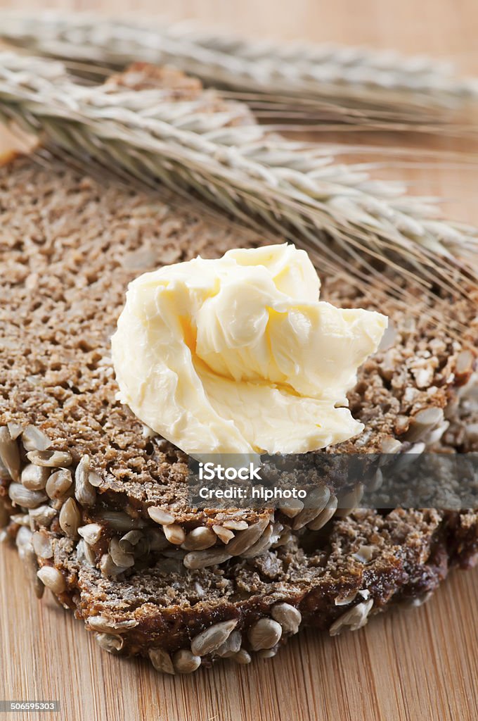 Wholemeal Bread with Butter Wholemeal bread with butter as closeup on a chopping board 7-Grain Bread Stock Photo