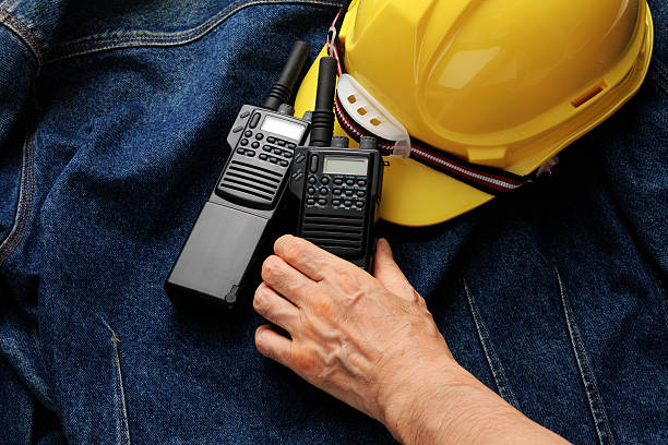 Close-up of walkie-talkies and construction hard hat with hand on denim jacket with copy space.