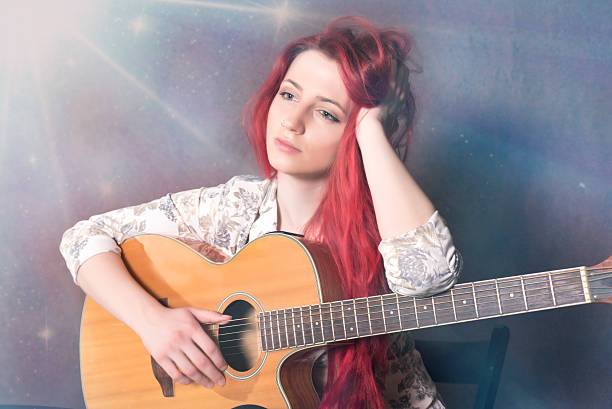 istock Conceived red haired girl with a guitar 506596062
