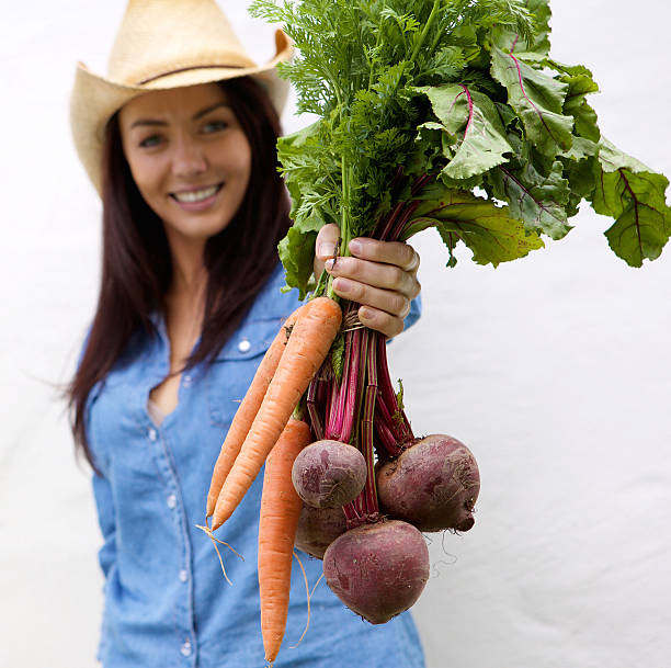 Smiling woman holding carrots and beets