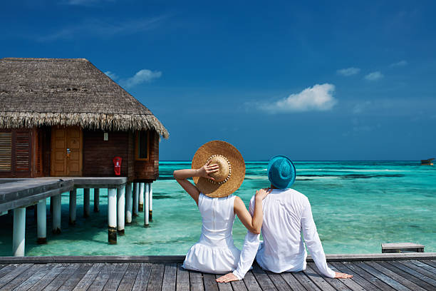 pareja en un embarcadero en la playa de maldivas - maldivas fotografías e imágenes de stock