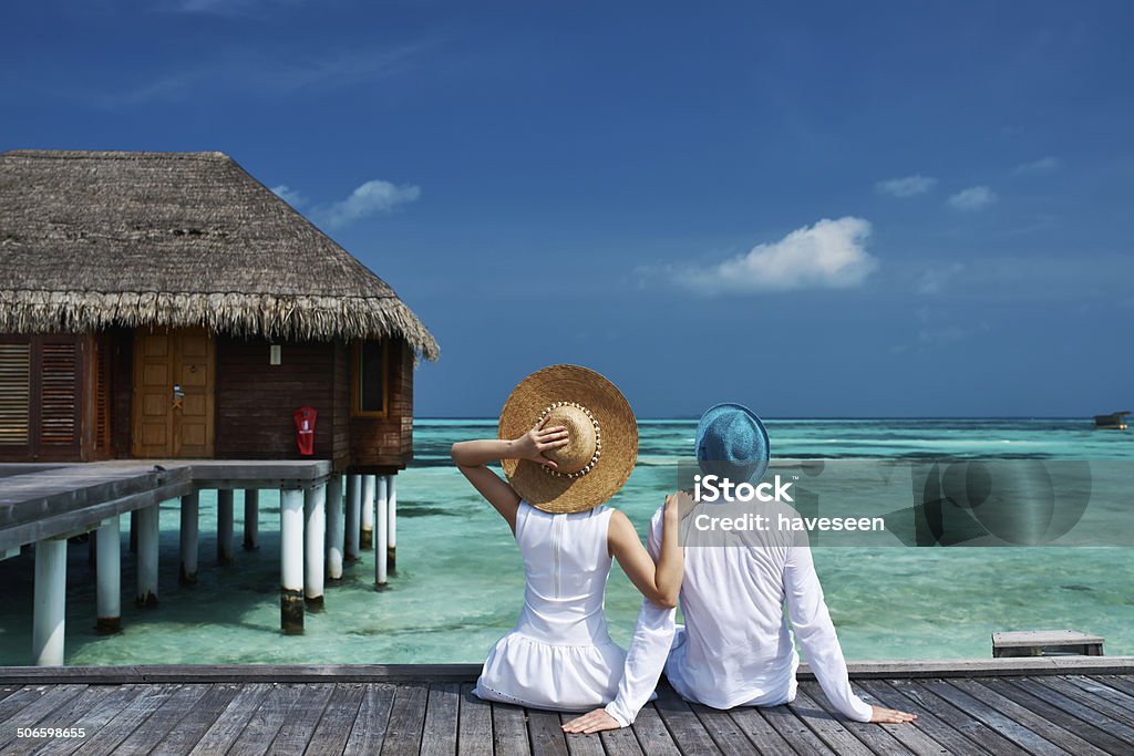 Couple on a beach jetty at Maldives Couple on a tropical beach jetty at Maldives Couple - Relationship Stock Photo