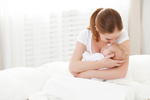 Cute newborn baby sleeping on her single mother in the living room. Copy space.
