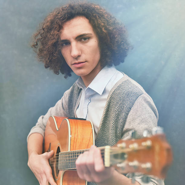 istock Young man with long hair playing guitar. 506599732