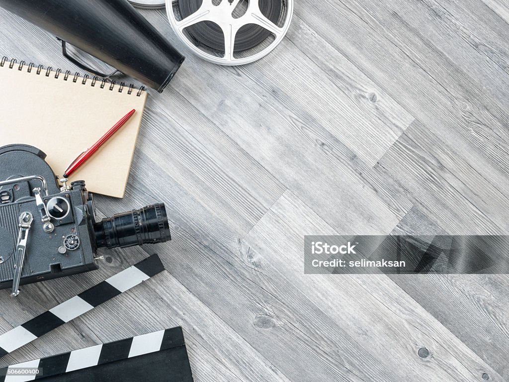 Cinema Film Production Equipments On Floor Film slate,movie video camera,notepad,pen,megaphone,film reel and film slate on the gray wooden floor.The photo was shot from directly above view point.Copy space on the right side of frame.The notepad is blank.No people are seen in frame.Shot with medium format camera Hasselblad in studio. Film Slate Stock Photo