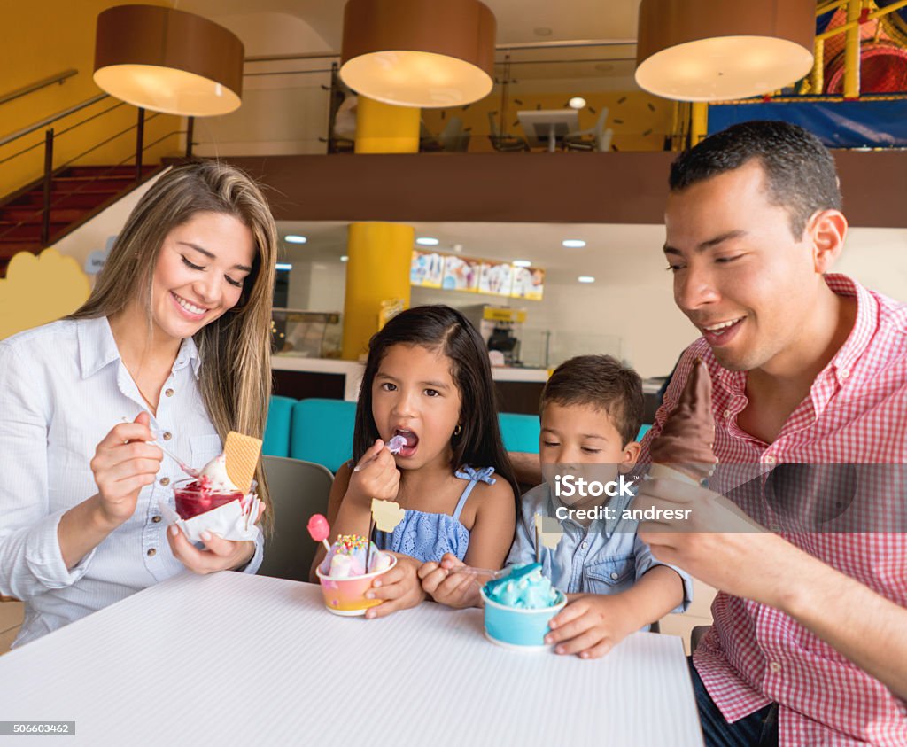 Happy family eating an ice cream Happy Latin American family eating an ice cream at an ice cream shop and smiling Family Stock Photo