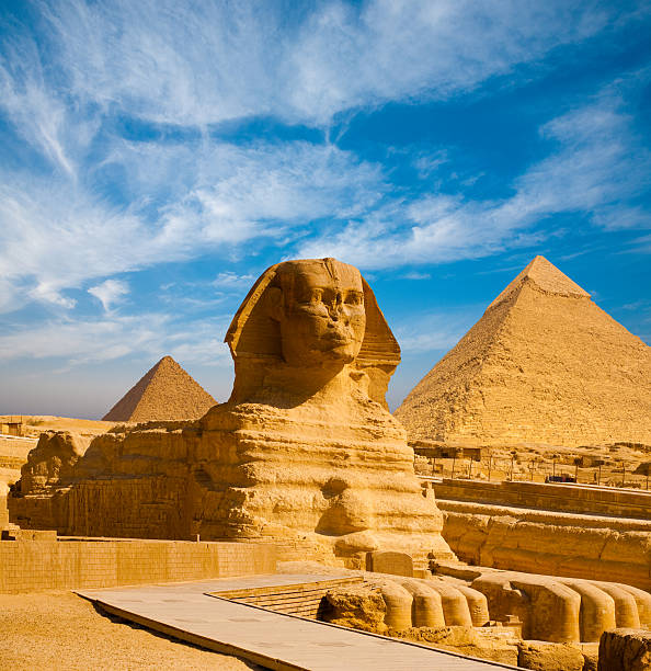 Full Sphinx Profile Pyramids Walkway Giza Full profile of Great Sphinx including pyramids of Menkaure and Khafre in the background on a clear sunny, blue sky day in Giza, Cairo, Egypt with no people cairo africa egypt built structure stock pictures, royalty-free photos & images