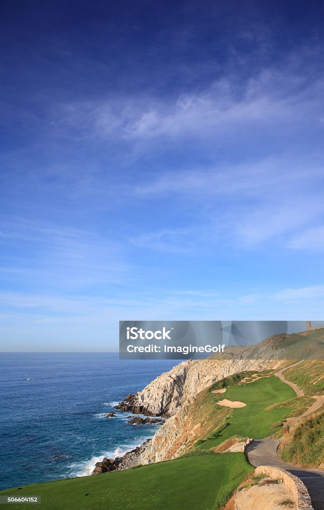 Beautiful Seaside Golf Hole in the Tropics A beautiful image of a golf course in a tropical desert destination of Los Cabos, Mexico. Nobody is in the image. Image shows the beautiful topography of this stunning golf destination. The best in Mexico, perhaps the entire tropics! The flag is fluttering in the breeze and a beautiful residential area beside the Pacific Ocean. Nobody is in the image. Classic golf course scenic with bunkering and excellent turf conditions and beautiful ocean backdrop behind the green. Los Cabos Stock Photo