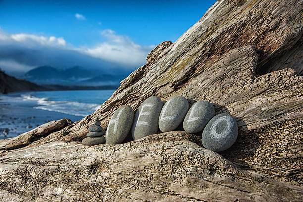 'hello' written in stones laying on driftwood at beach stock photo