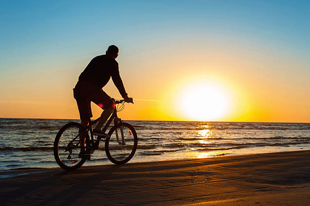 istock Man cyclist silhouette on blue sky and multicolored sunset background. 506606494