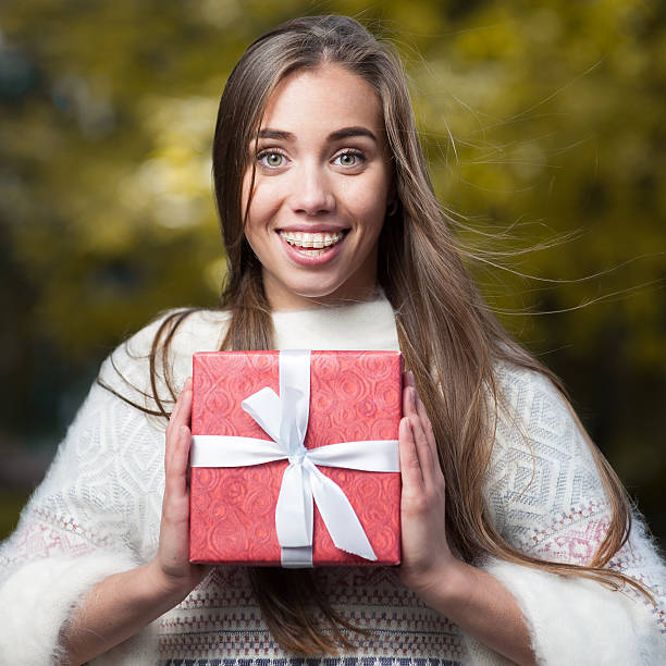 istock attractive young woman holding red present 506608470