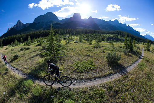 A woman leads a man in a cross country mountain bike race in the Rocky Mountains of Canada.