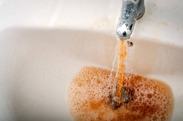 sporca marrone acqua sporca da un rubinetto corsa - lavandino rotto foto e immagini stock