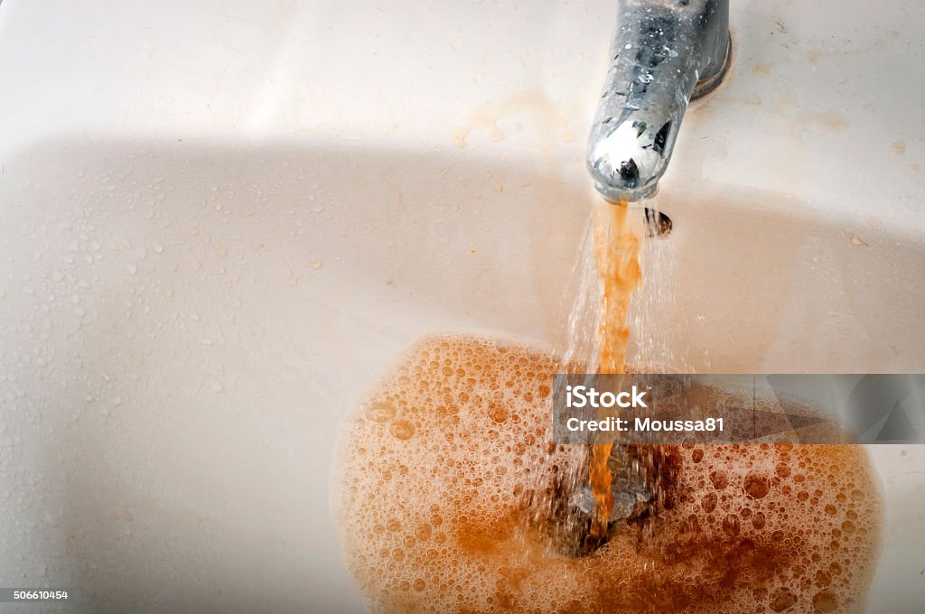 Dirty brown water running from a filthy faucet Grungy image of dirty brown water running from a water stained faucet Water Stock Photo