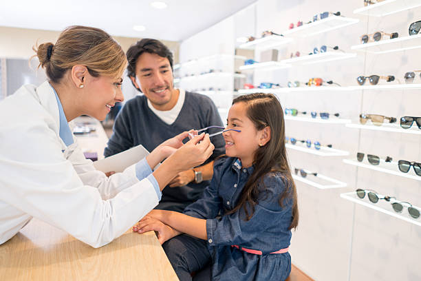 Girl at the optician's shop trying new glasses Happy girl at the optician's shop with her father and the eye doctor and trying new glasses optometry stock pictures, royalty-free photos & images