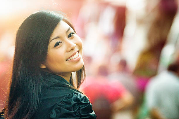 glückliche junge frau lächelnd strahlende indonesischen über der schulter - confident gegenlicht kopfbild stadt over the shoulder stock-fotos und bilder