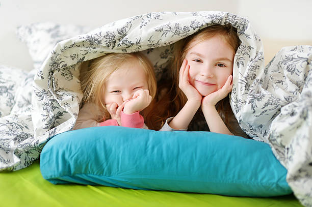 istock Two little sisters playing in bed 506618944