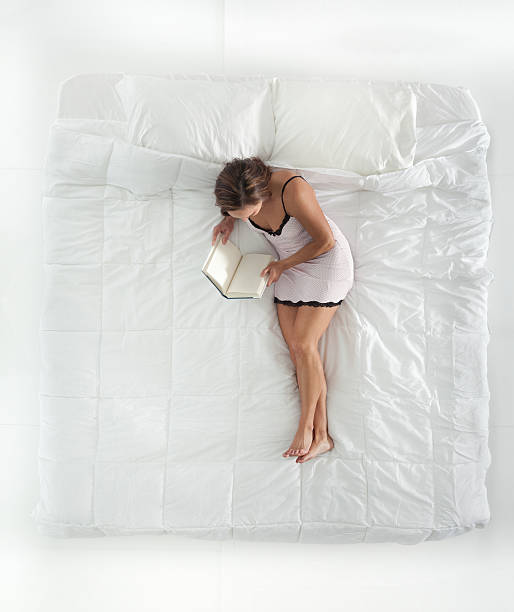 istock Above view of woman on bed & reading book 506624449