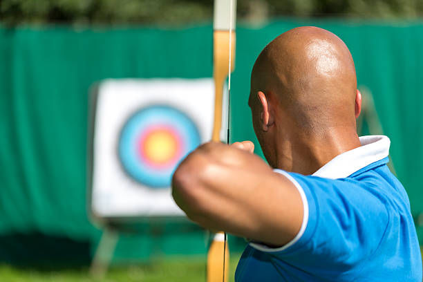 Bowman or archer aiming at target with bow and arrow